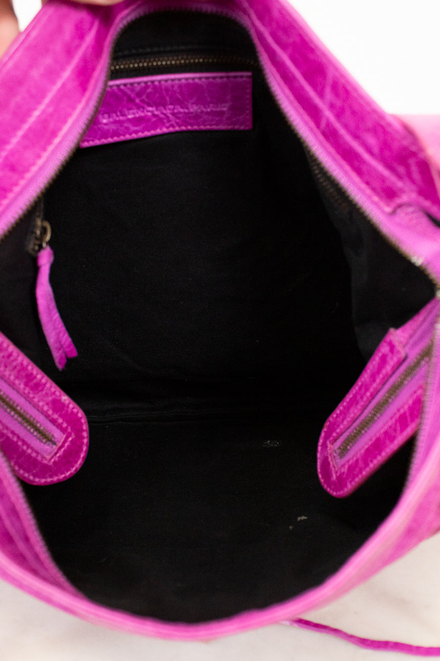Close-up of a pink handbag with a black interior on a light background