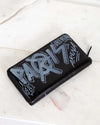 Black wallet with gray and white text on a light marble background