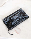 Black wallet with graphic design on a white marble surface