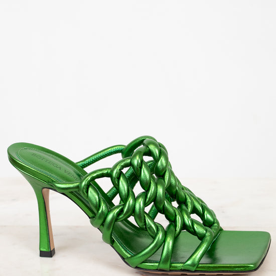 Green high-heeled sandal with chain design on a white background