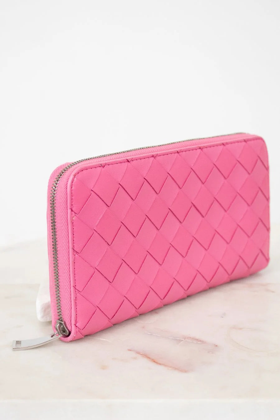 Pink quilted wallet on a light pink surface