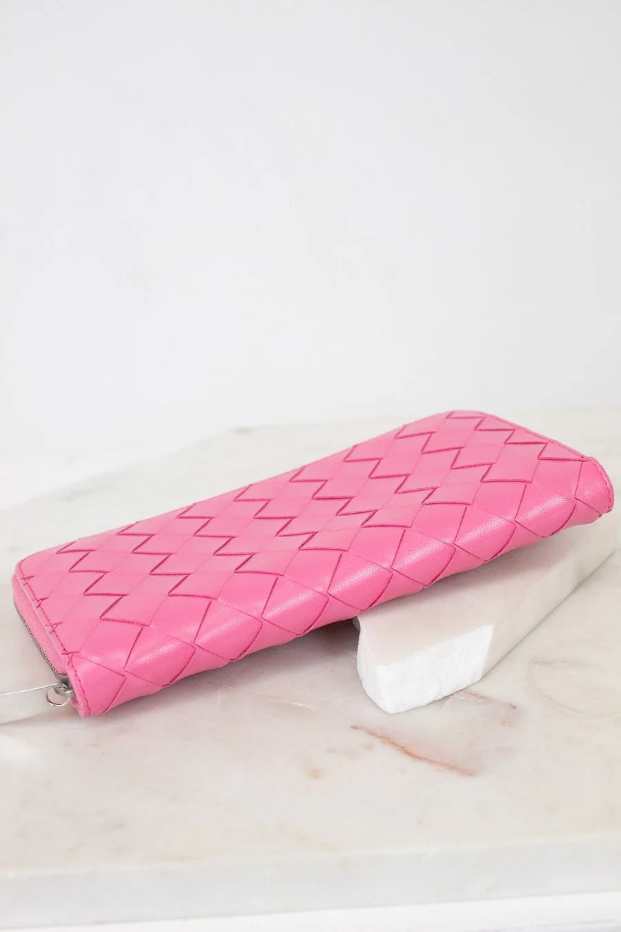 Pink quilted wallet on a light marble surface