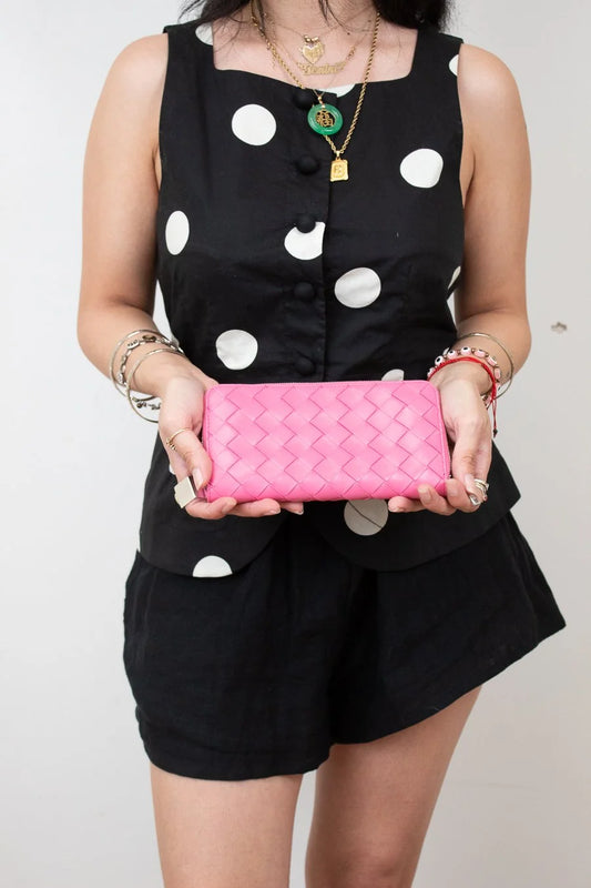 Person holding a pink wallet against a plain background