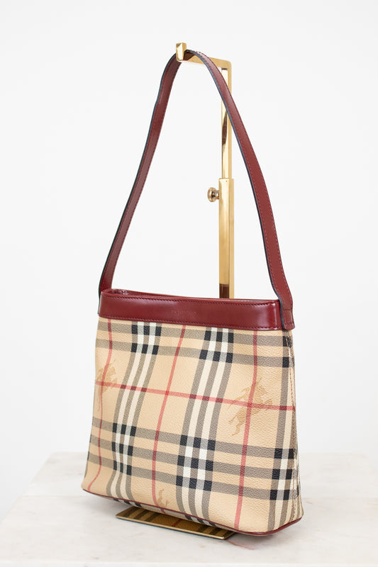 Designer handbag with check pattern and brown leather strap on a white background