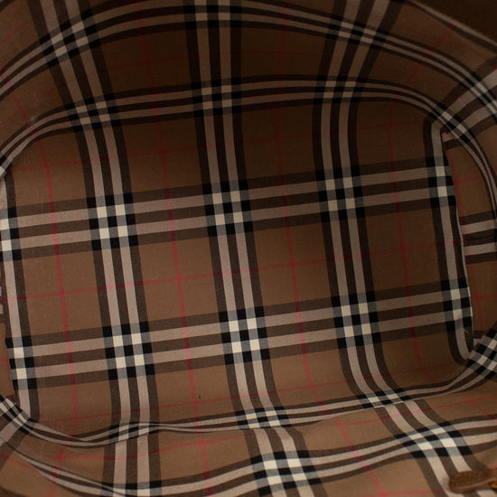 Close-up of a brown leather bag with plaid pattern on a light background