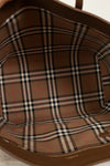 Close-up of a brown leather bag with plaid pattern on a light background