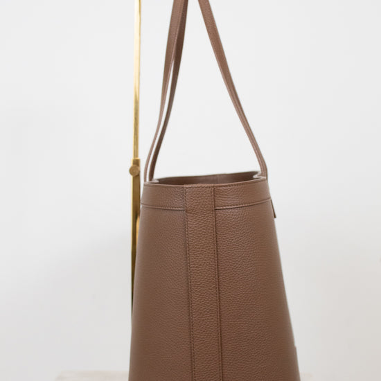Brown leather tote bag with a strap on a white background
