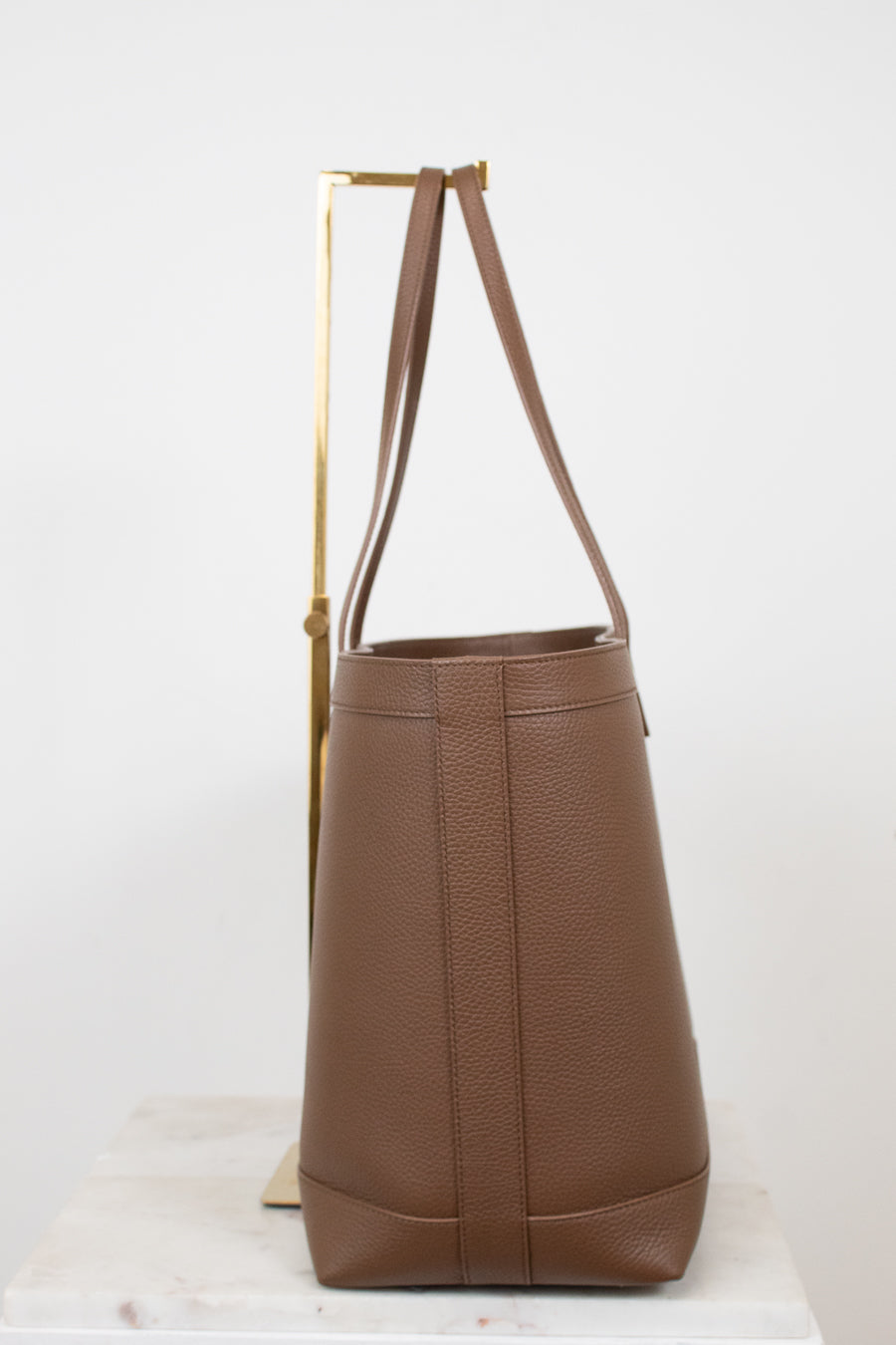 Brown leather tote bag with a strap on a white background