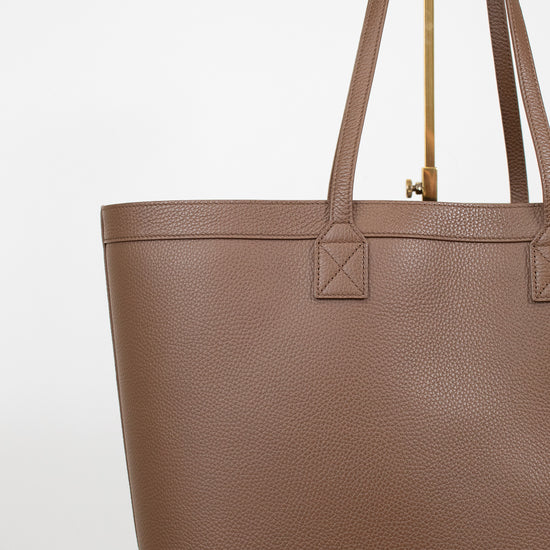 Brown tote bag with a gold zipper on a white background