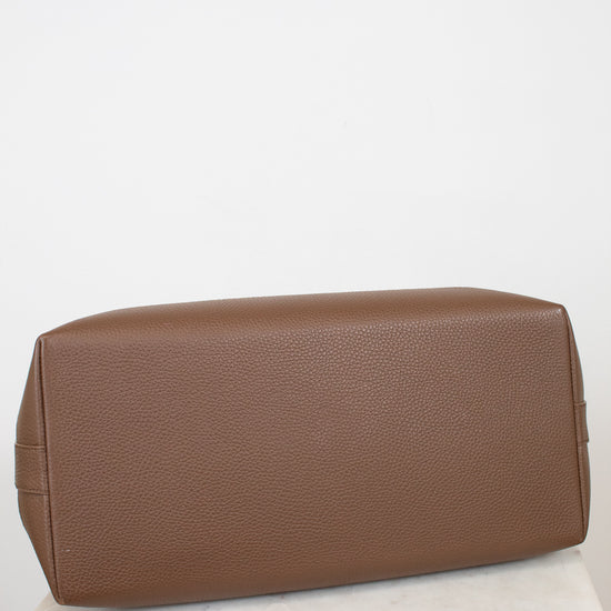 Brown leather bag on a white surface with a light gray background