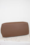 Brown leather bag on a white surface with a light gray background