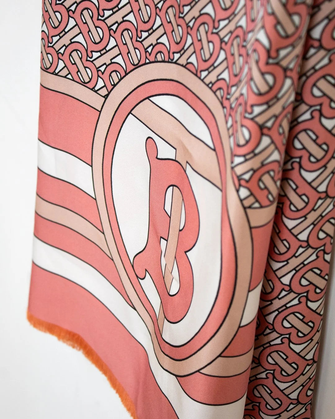 Close-up of a pink and white patterned fabric with a prominent 'B' logo.