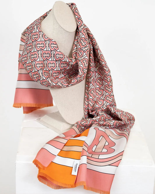 Colorful scarf with pink and orange logo pattern on a mannequin against a white background
