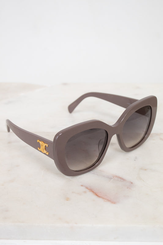 Sunglasses with a gold logo on a marble surface