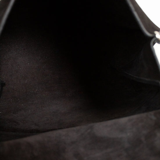 Close-up of a black leather bag with a hand holding it open.