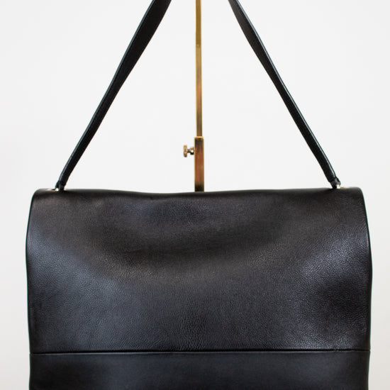 Black leather handbag with a strap on a white background