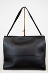 Black leather handbag with a strap on a white background