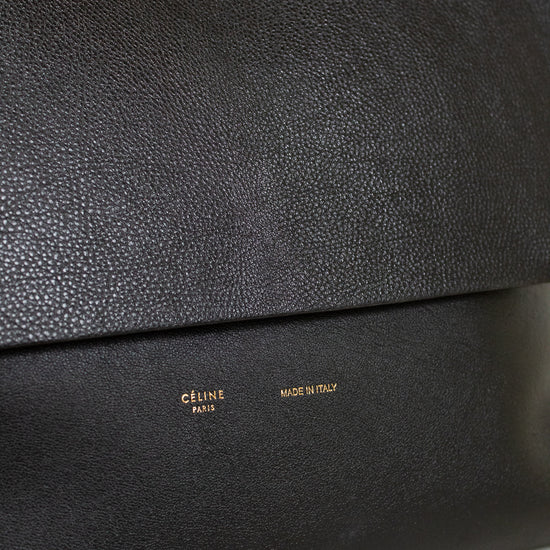 Close-up of a black leather clutch bag with 'Celine' branding on a marble surface.