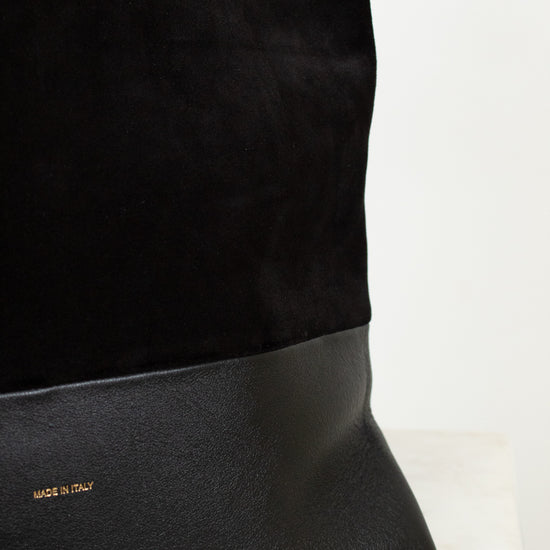 Black handbag with gold logo on a light background