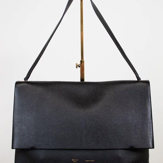 Black leather handbag with a strap on a white background