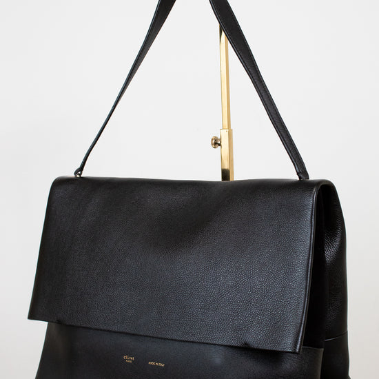 Black leather handbag with a gold handle on a white background