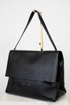 Black leather handbag with a gold handle on a white background
