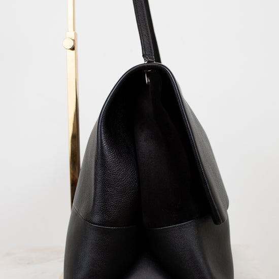 Black leather handbag on a light gray background