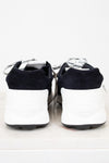 Pair of Chanel navy blue sneakers with white laces on a light gray background
