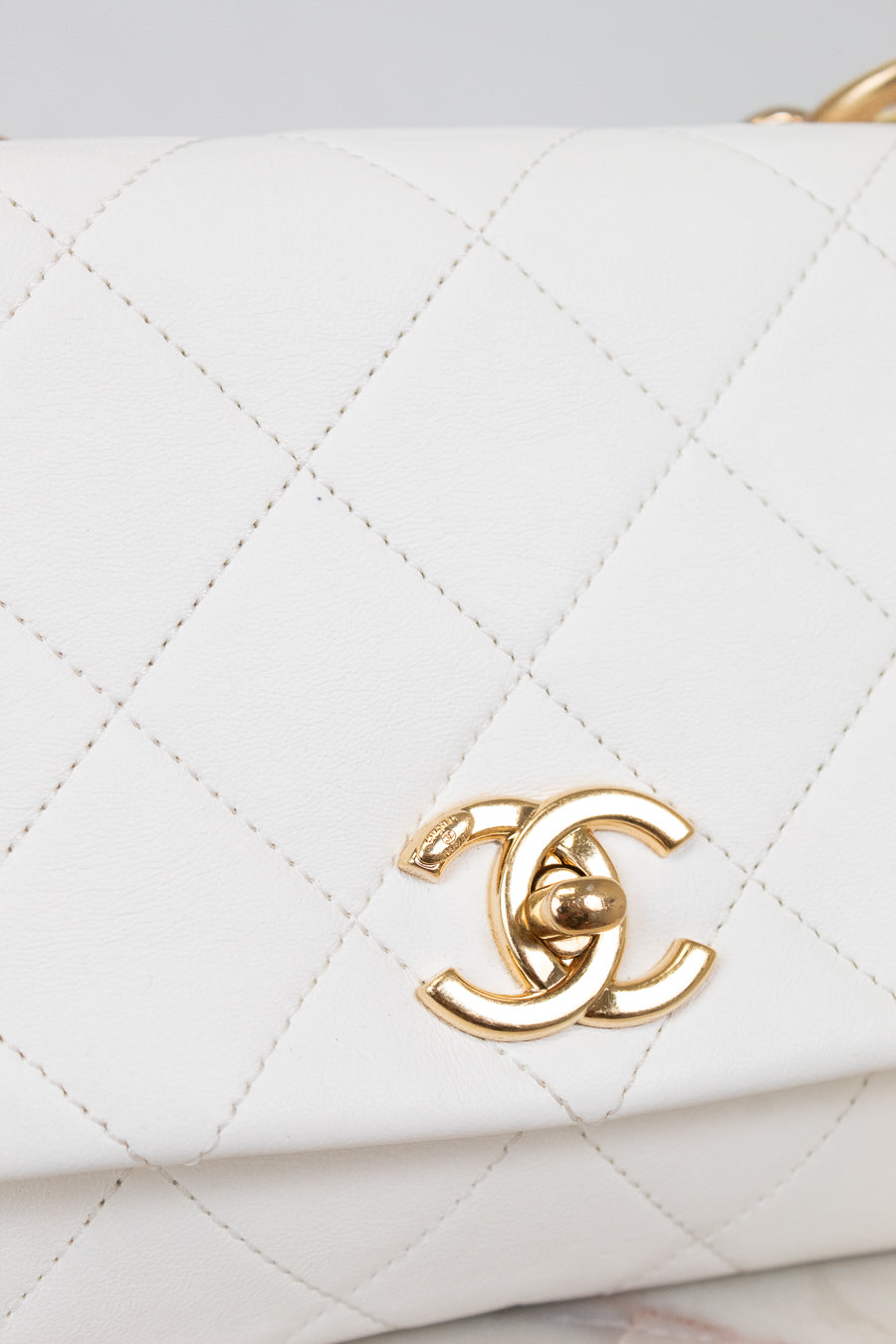 White quilted handbag with gold CC logo on a light gray background