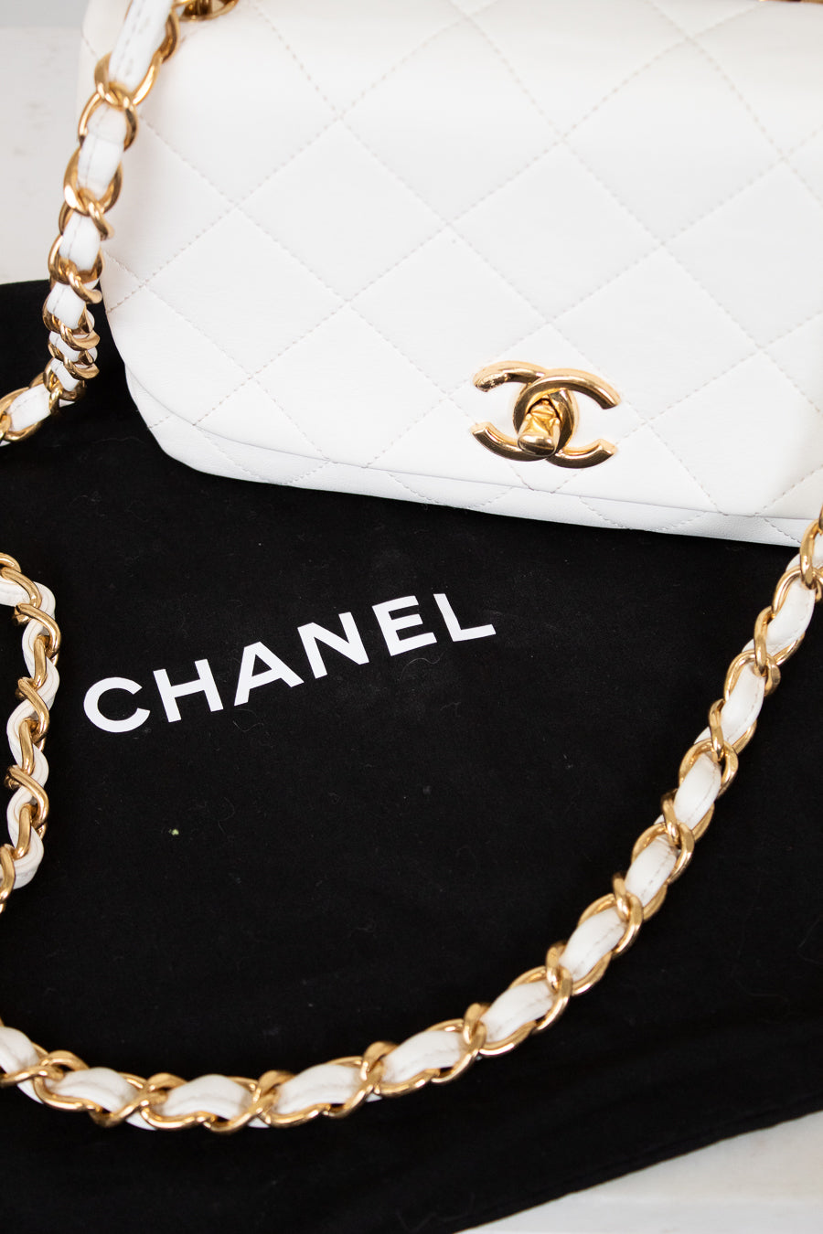 White Chanel handbag with gold chain on a black background