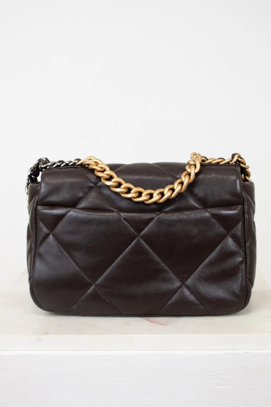 Dark Brown quilted handbag with a gold chain strap on a white background