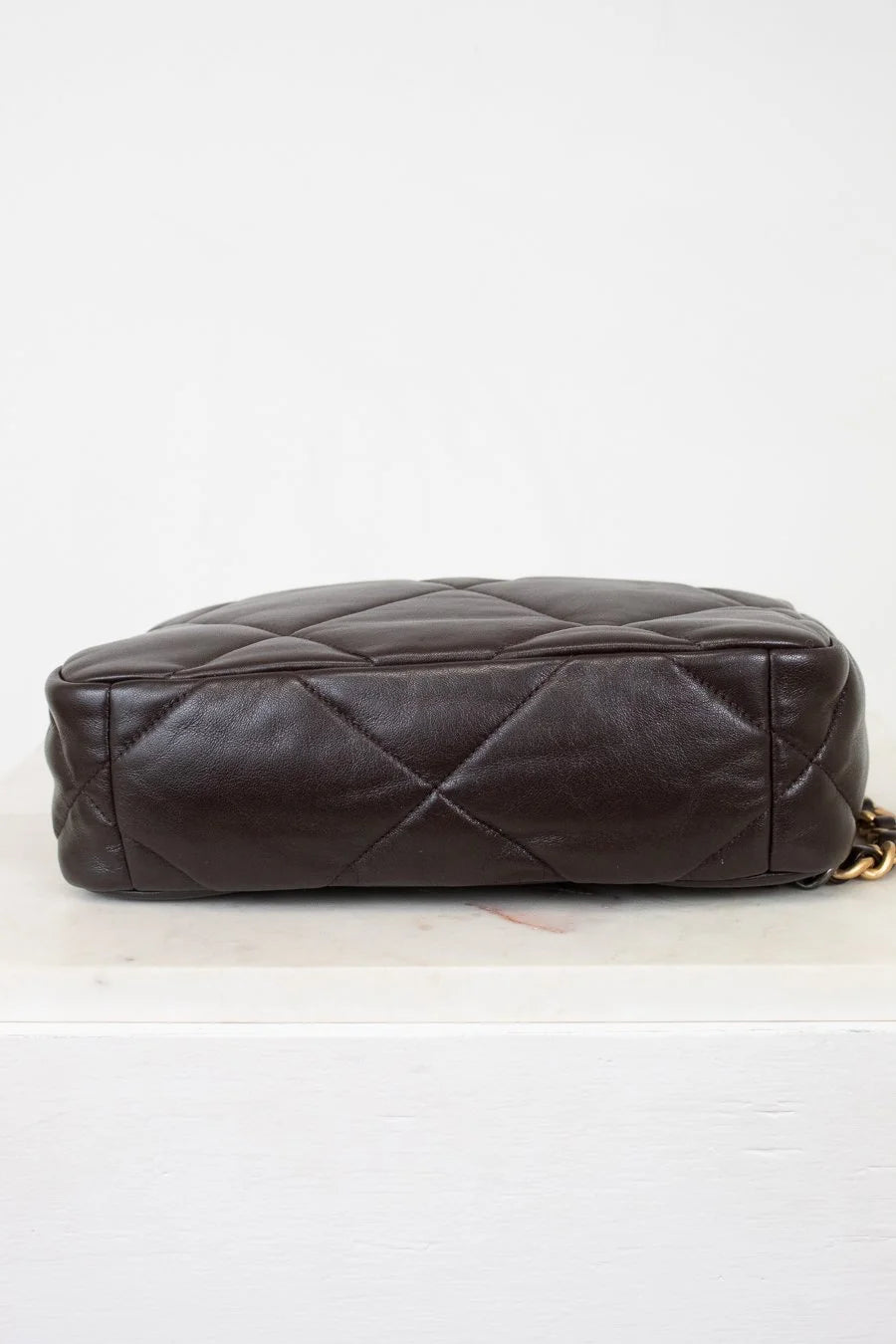 Brown quilted handbag on a light gray background