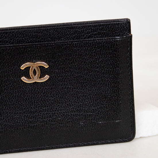Black leather wallet with gold Chanel logo on a white background