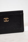 Black leather wallet with gold Chanel logo on a white background