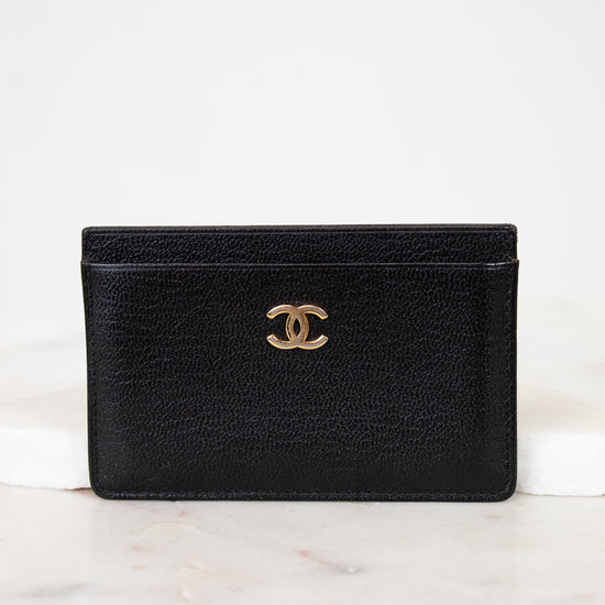 Black leather wallet with gold CC logo on a white marble surface