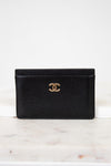 Black leather wallet with gold CC logo on a white marble surface