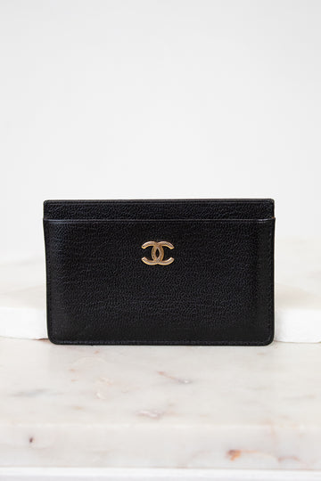 Black leather wallet with gold CC logo on a white marble surface