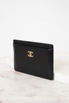 Black leather cardholder with gold logo on a white background