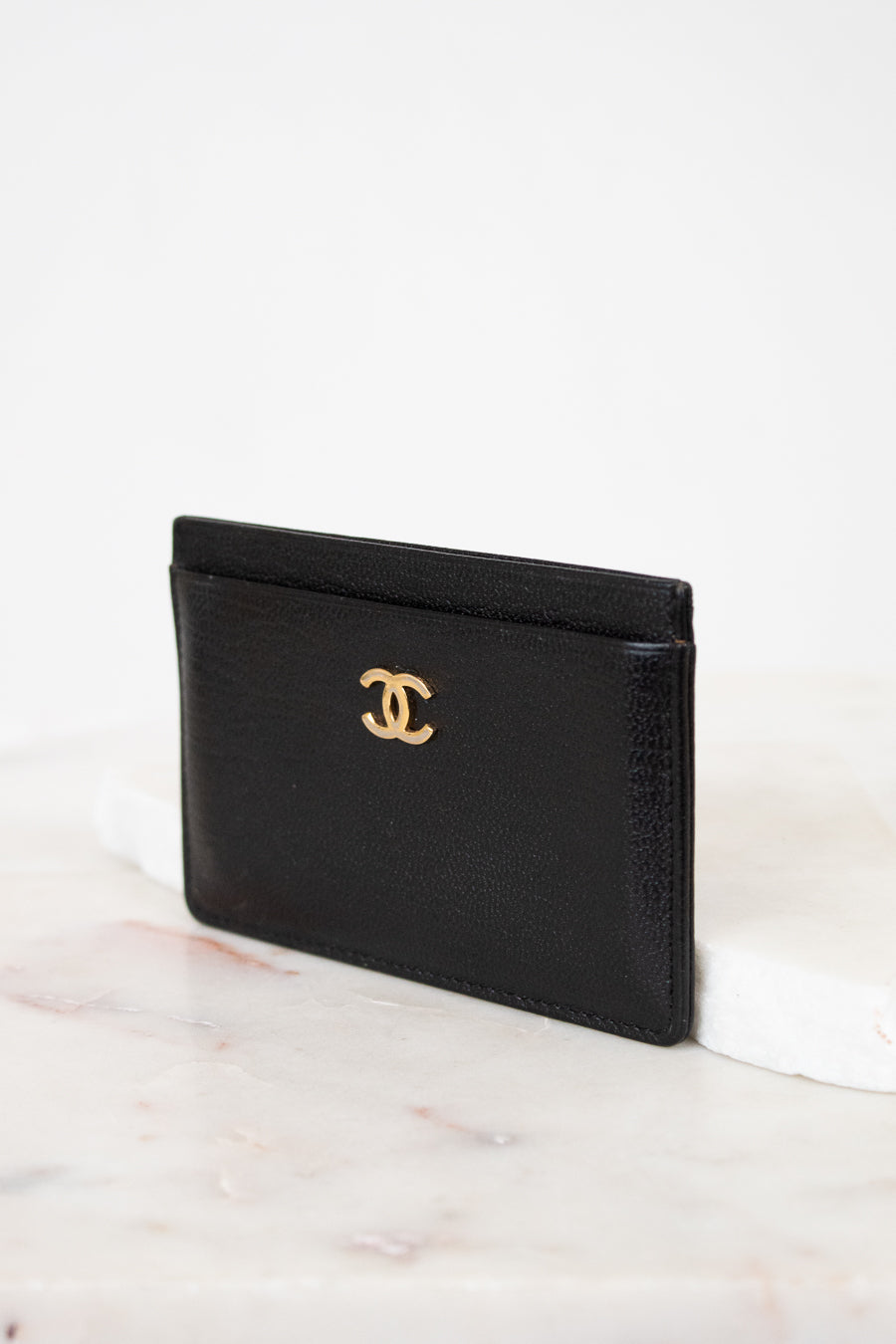 Black leather cardholder with gold logo on a white background