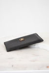 Black wallet with gold logo on a light marble surface