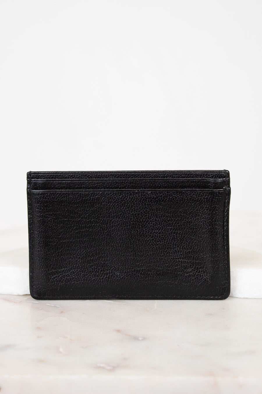 Black leather wallet on a white marble surface