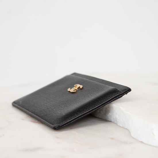 Black leather wallet with gold emblem on a marble surface