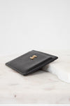 Black leather wallet with gold emblem on a marble surface