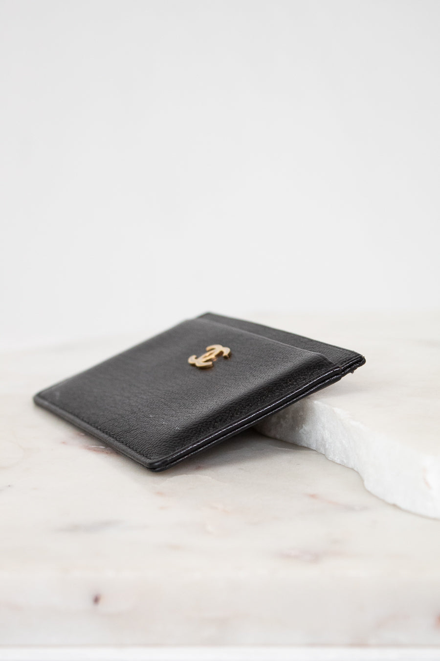 Black leather wallet with gold emblem on a marble surface