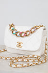 White quilted handbag with gold chain strap on a light gray background