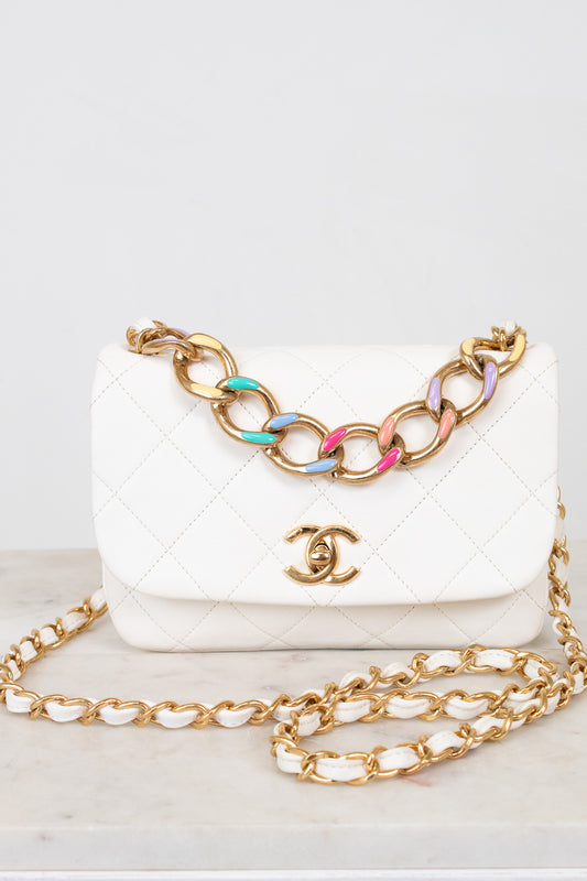 White quilted handbag with gold chain strap on a light background