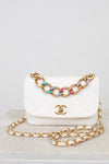 White Chanel handbag with gold chain on a light gray background