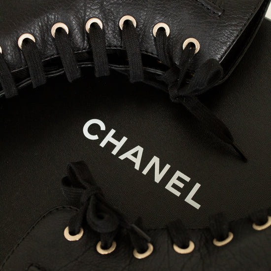 Black leather Chanel shoes with laces on a light background