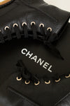 Black leather Chanel shoes with laces on a light background