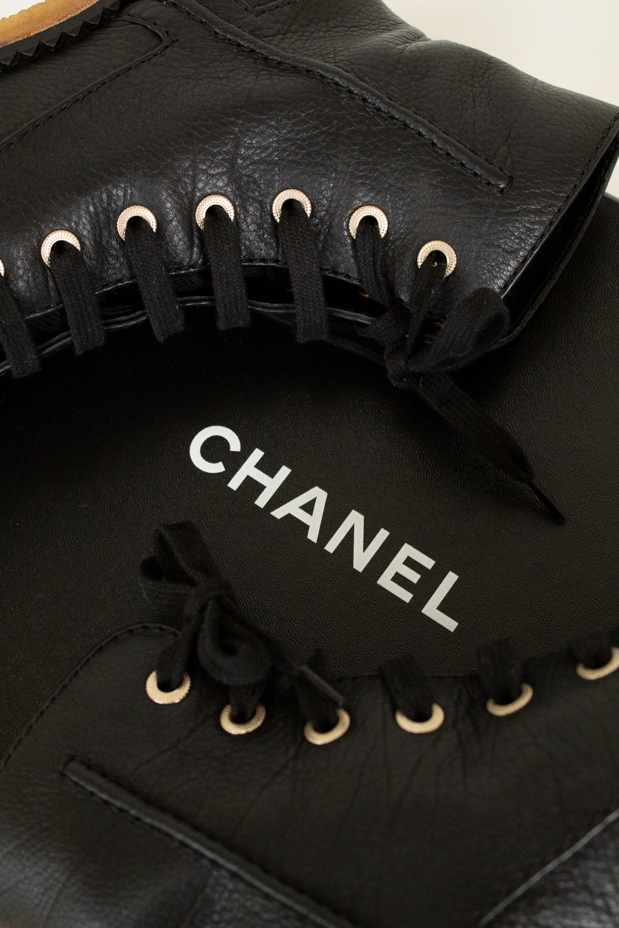 Black leather Chanel shoes with laces on a light background